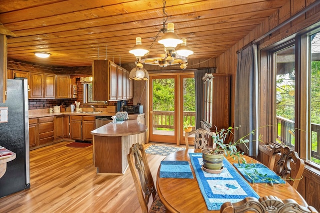 interior space featuring hanging light fixtures, light wood-type flooring, wooden ceiling, wooden walls, and sink