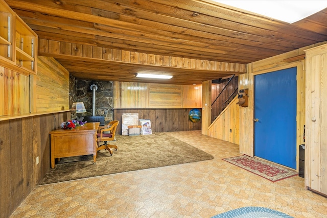 basement featuring tile floors, a wood stove, wooden ceiling, and wood walls