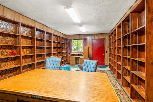 unfurnished office featuring wooden walls and a textured ceiling