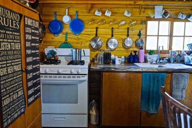 kitchen featuring white gas range, sink, and wooden walls