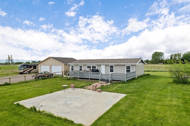 rear view of house featuring a deck, a garage, a yard, and an outdoor structure