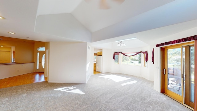 unfurnished living room with lofted ceiling, light carpet, and a chandelier