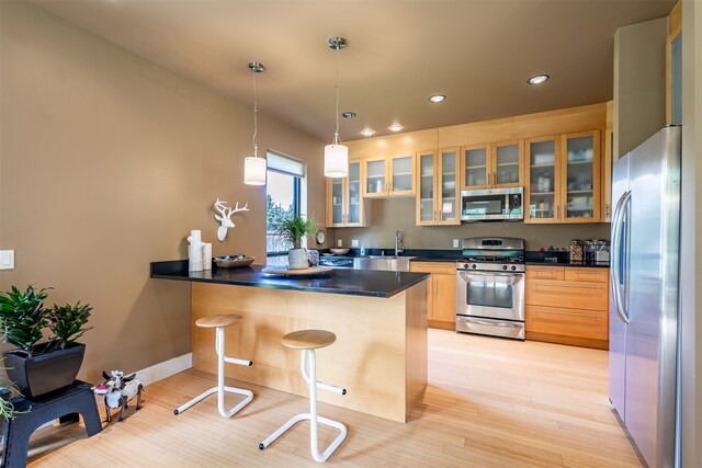 kitchen featuring light hardwood / wood-style floors, kitchen peninsula, appliances with stainless steel finishes, a breakfast bar, and pendant lighting