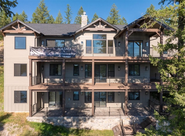 198 Blaine Lakeshore Dr, Kalispell, MT 59901 - rear view of house featuring board and batten siding, a chimney, and a shingled roof