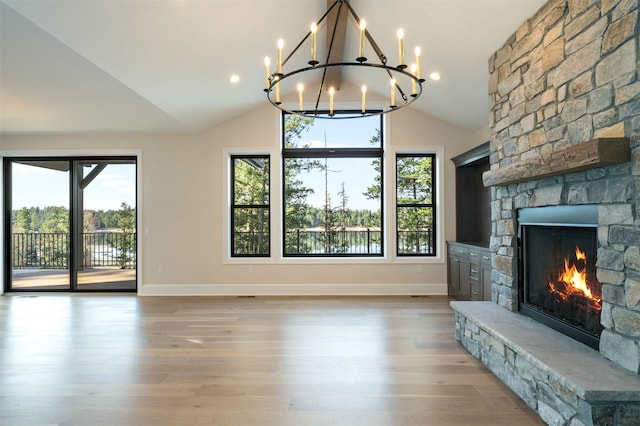 198 Blaine Lakeshore Dr, Kalispell, MT 59901 - unfurnished living room featuring baseboards, a chandelier, a fireplace, lofted ceiling, and light wood finished floors