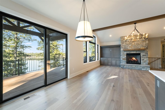 198 Blaine Lakeshore Dr, Kalispell, MT 59901 - unfurnished living room with light wood finished floors, visible vents, a stone fireplace, and lofted ceiling with beams