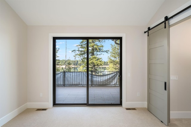 198 Blaine Lakeshore Dr, Kalispell, MT 59901 - unfurnished bedroom featuring vaulted ceiling, light carpet, a barn door, visible vents, and access to exterior