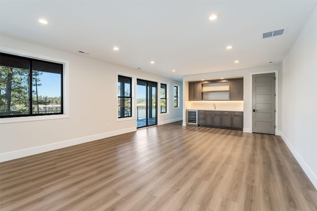 198 Blaine Lakeshore Dr, Kalispell, MT 59901 - unfurnished living room with bar area, recessed lighting, light wood finished floors, and wine cooler