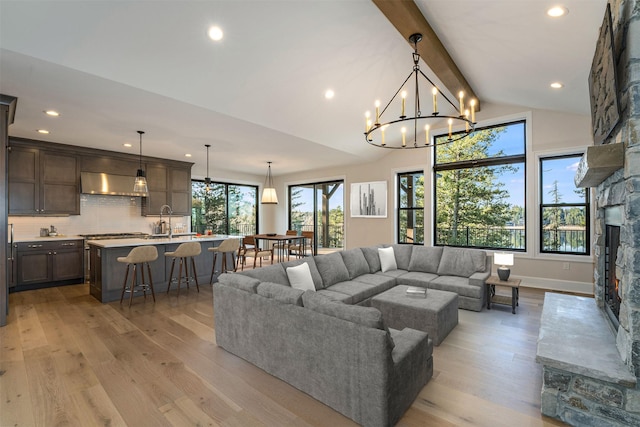 198 Blaine Lakeshore Dr, Kalispell, MT 59901 - living area featuring vaulted ceiling with beams, light wood finished floors, a chandelier, and a fireplace