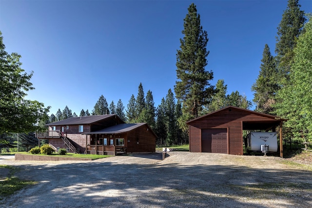 view of front facade featuring a wooden deck, a garage, an outdoor structure, and a carport