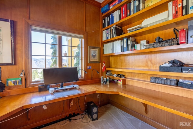 office space with built in desk and wood walls