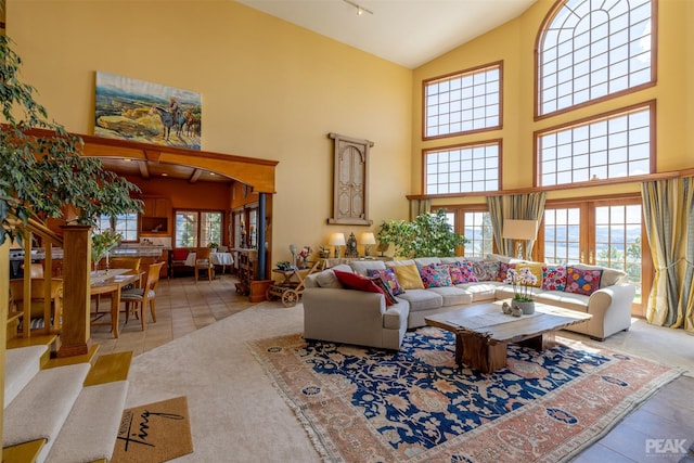 living room featuring light tile patterned flooring, a healthy amount of sunlight, and high vaulted ceiling