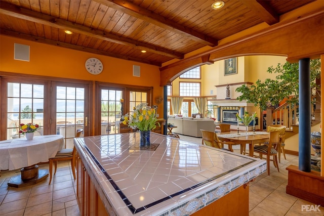 kitchen featuring tile countertops, beamed ceiling, a center island, light tile patterned floors, and wooden ceiling