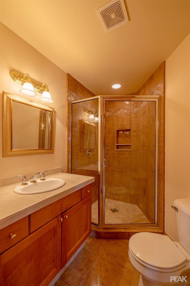 bathroom with toilet, vanity, tile patterned floors, and a shower with shower door