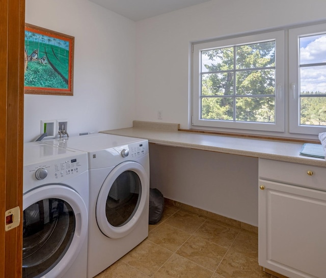 clothes washing area with separate washer and dryer and cabinets