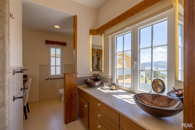 bathroom featuring french doors, toilet, tile walls, vanity, and a mountain view