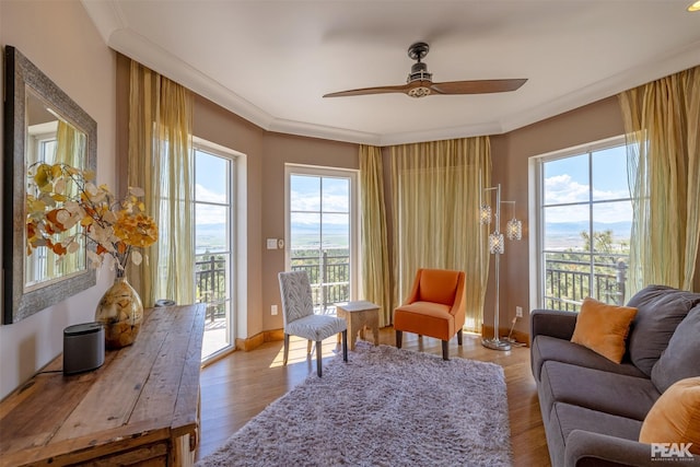 living area with crown molding, light hardwood / wood-style flooring, and ceiling fan