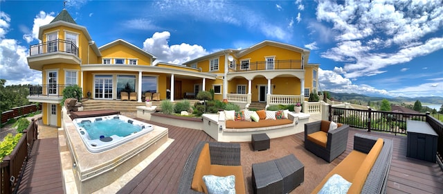 rear view of property featuring a balcony, an outdoor hangout area, and a deck with mountain view