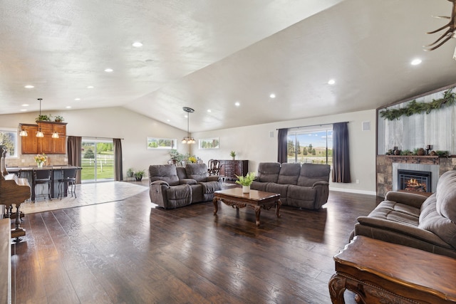 living room with a tile fireplace, lofted ceiling, and dark wood-type flooring