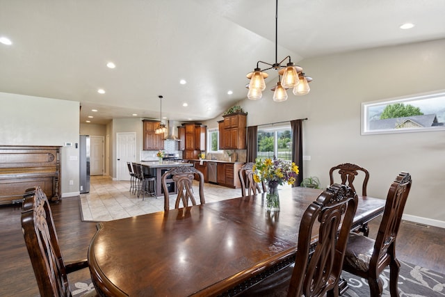 dining area featuring lofted ceiling, light hardwood / wood-style flooring, and an inviting chandelier