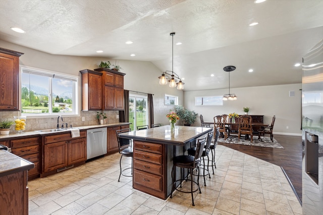 kitchen with dishwasher, hanging light fixtures, vaulted ceiling, a kitchen bar, and a kitchen island