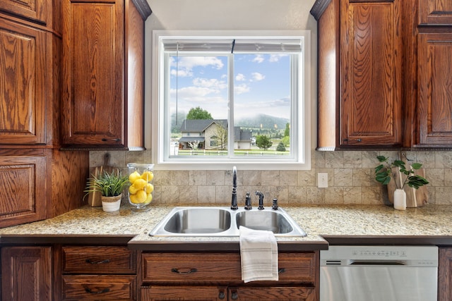 kitchen featuring dishwasher, light stone counters, sink, and tasteful backsplash