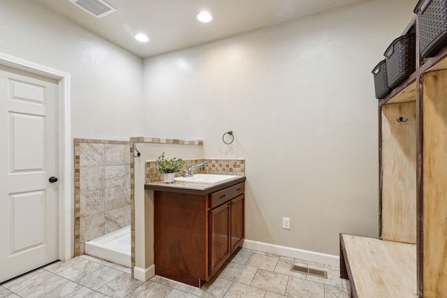 bathroom with tiled shower, vanity, and tile walls