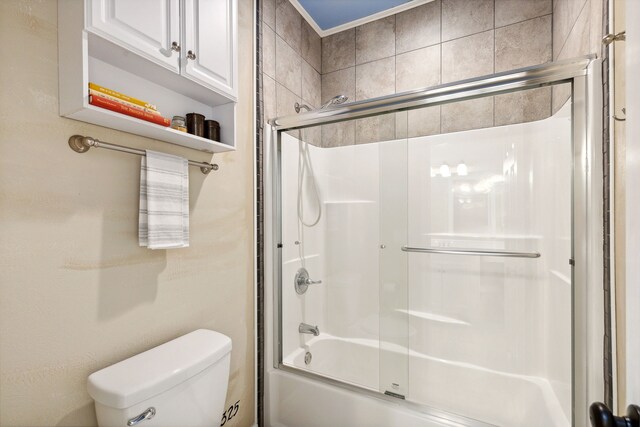 bathroom featuring toilet and combined bath / shower with glass door