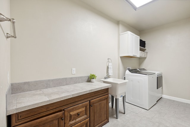 laundry area with washer and clothes dryer, light tile patterned flooring, and cabinets