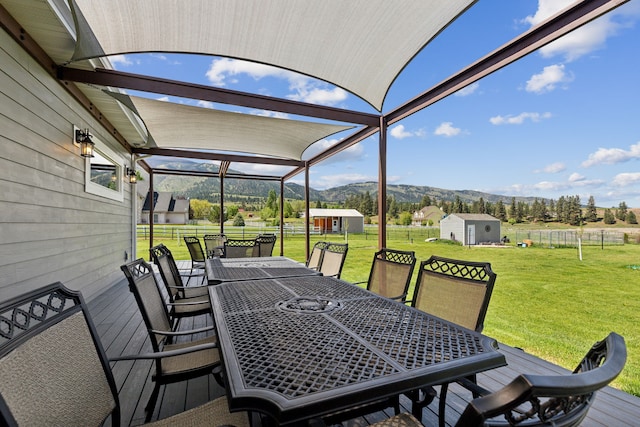 wooden deck featuring a lawn, a mountain view, and a storage shed