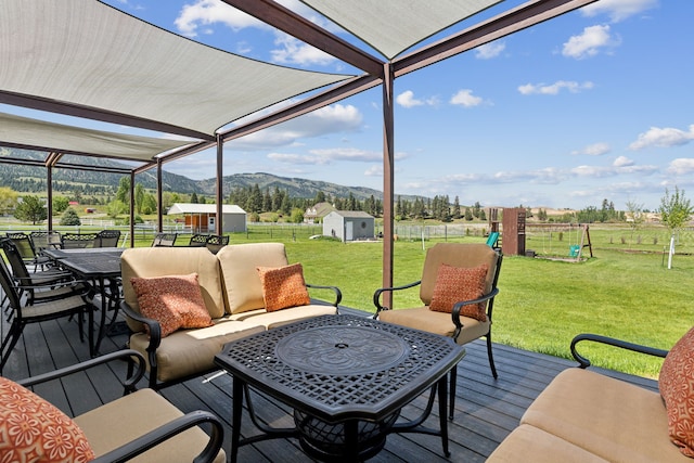 deck with a mountain view, an outdoor living space, a playground, and a lawn