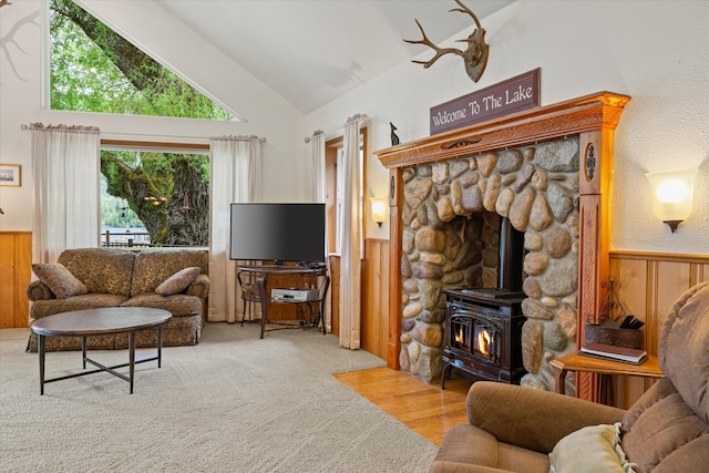 living room featuring high vaulted ceiling, carpet, and a wood stove