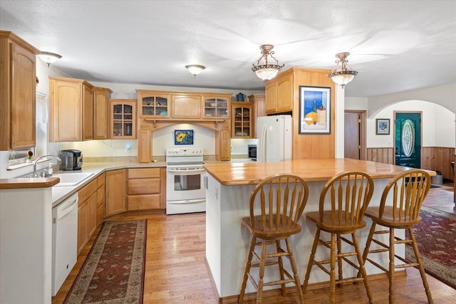 kitchen with a center island, light wood-type flooring, white appliances, wooden counters, and sink