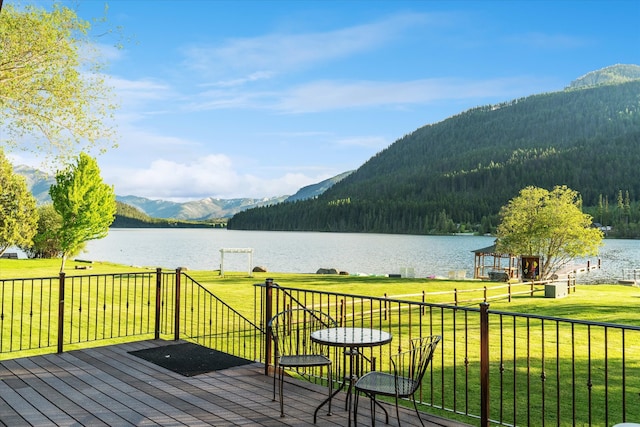 wooden terrace with a water and mountain view and a yard