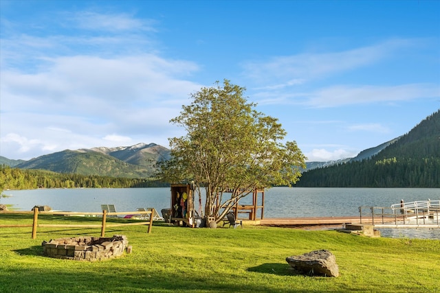 exterior space featuring a water and mountain view, a boat dock, and a lawn