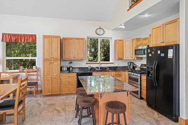 kitchen with a center island, vaulted ceiling, a wealth of natural light, and black appliances