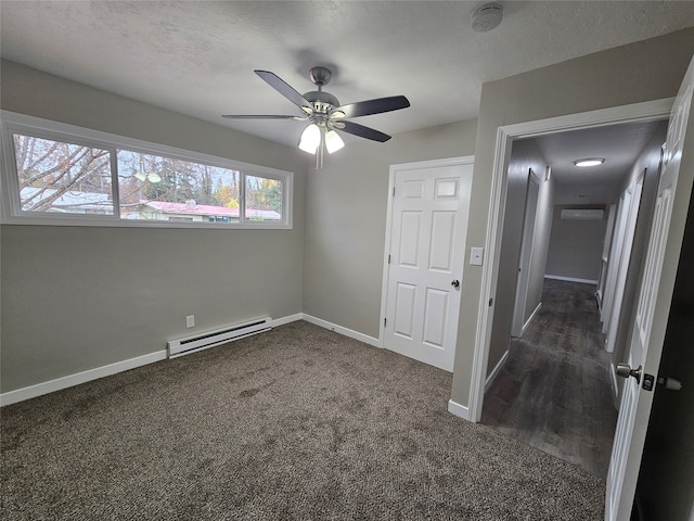 spare room with baseboard heating, dark carpet, and ceiling fan