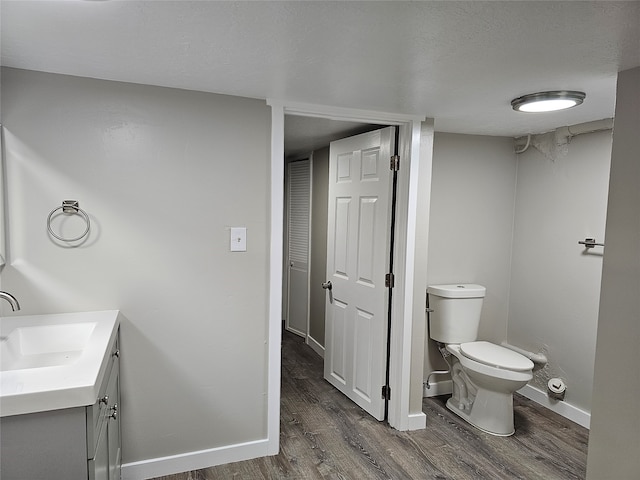 bathroom with a textured ceiling, wood-type flooring, toilet, and vanity