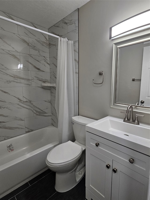 full bathroom with toilet, tile floors, shower / bath combo with shower curtain, vanity, and a textured ceiling