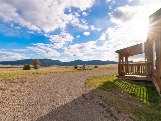 view of yard with a rural view and a deck with mountain view