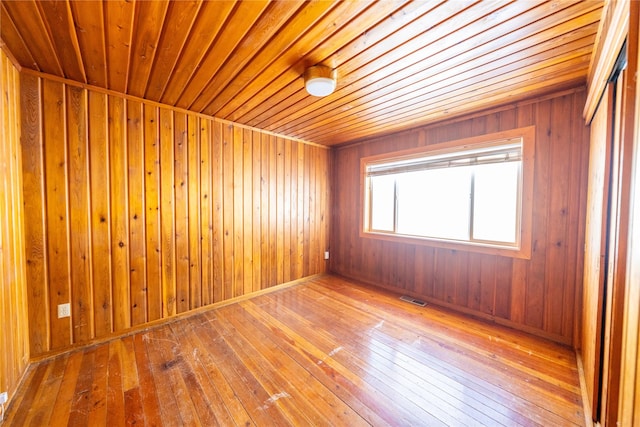 empty room with hardwood / wood-style flooring and wooden walls