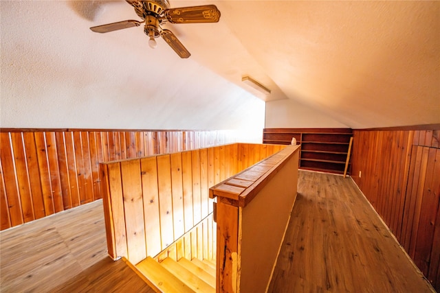 bonus room with ceiling fan, wood-type flooring, vaulted ceiling, and wood walls