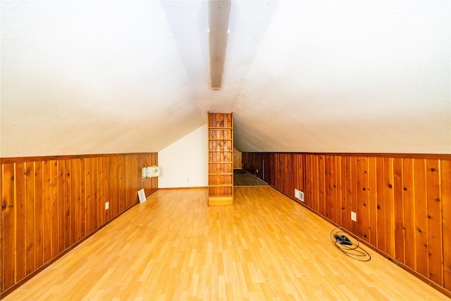 additional living space with vaulted ceiling, wooden walls, and hardwood / wood-style floors