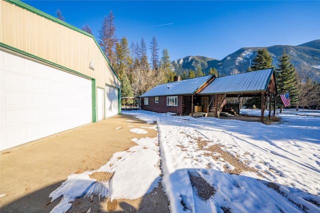 snow covered property with a garage and a mountain view