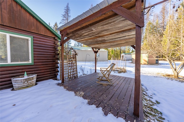 snow covered deck featuring a storage shed