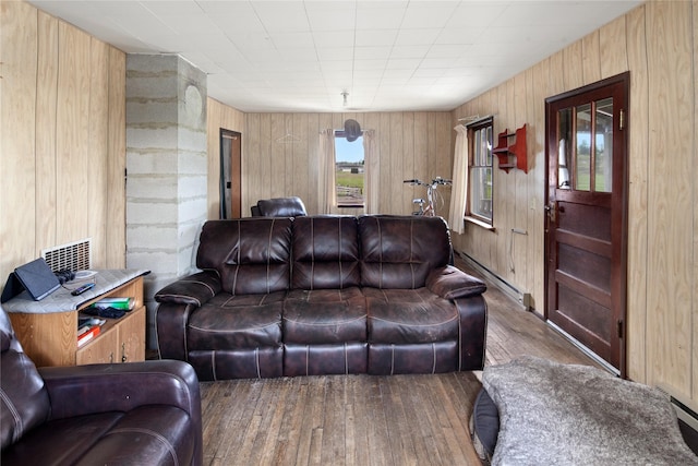 living room featuring wood walls, wood-type flooring, and a baseboard heating unit