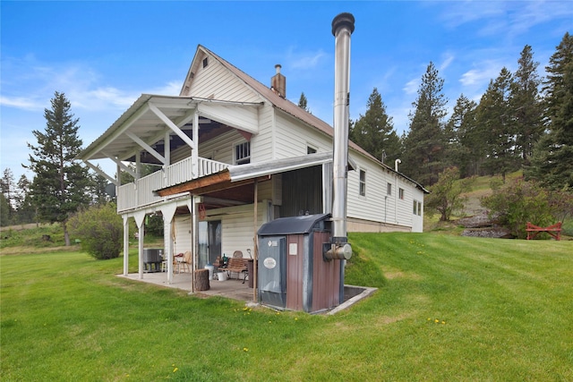 rear view of property featuring central air condition unit, a balcony, a patio area, and a lawn