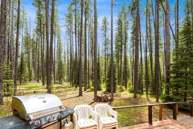 exterior space with grilling area, a view of trees, and a wooden deck