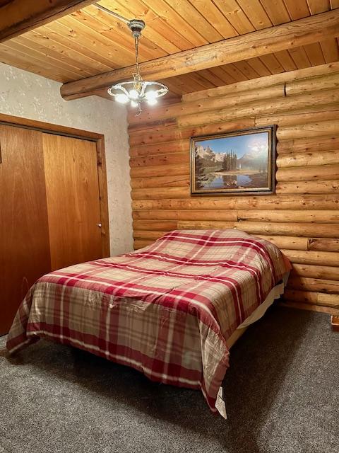 bedroom featuring log walls, wooden ceiling, beam ceiling, and carpet