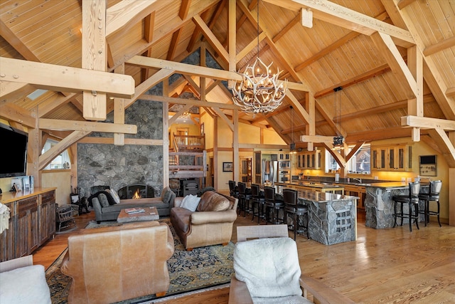 living room with an inviting chandelier, wooden ceiling, hardwood / wood-style flooring, beam ceiling, and a large fireplace